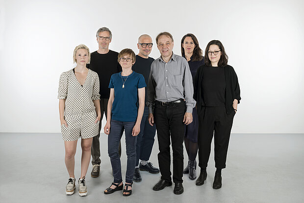 
            
                a group of standing people in front of a white wall: the mumok curatorial team
            
        