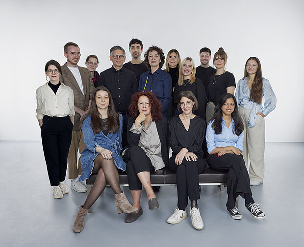
            
                a group of people in front of a white wall, four of them sitting on a bench in the foreground: the marketing and communication team at mumok
            
        