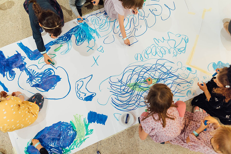 
            
                Kinder malen in blauen und grünen Farben auf einem großen weißen Papier
            
        