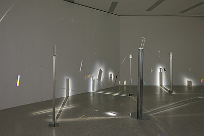 Liliane Lijn, Four Figures of Light, 1978, Installation, optical glass periscope prism, chromed spring steel with prisms, chromed perforated steel triangular upright, circular steel base, 188 x 243 cm; optical glass periscope prism, chromed spring steel with prisms, aluminium angle, steel blocks, 167 x 213 cm; optical glass periscope prism, aluminium angles, chromed steel blocks, 160 cm high; optical glass periscope prism, aluminium angles, chromed steel blocks, 147 cm high