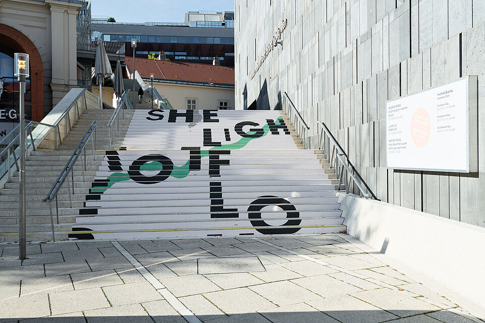 Stairs to mumok covered by Liliane Lijn's work Words to Walk On